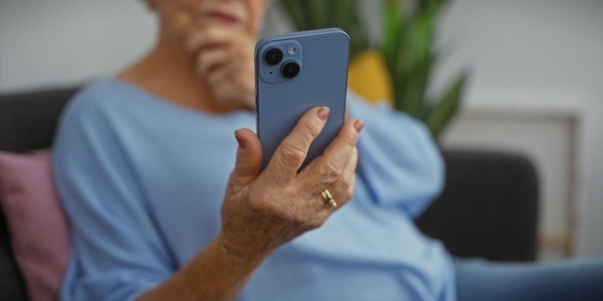 idős hölgy nézi a mobiltelefonját