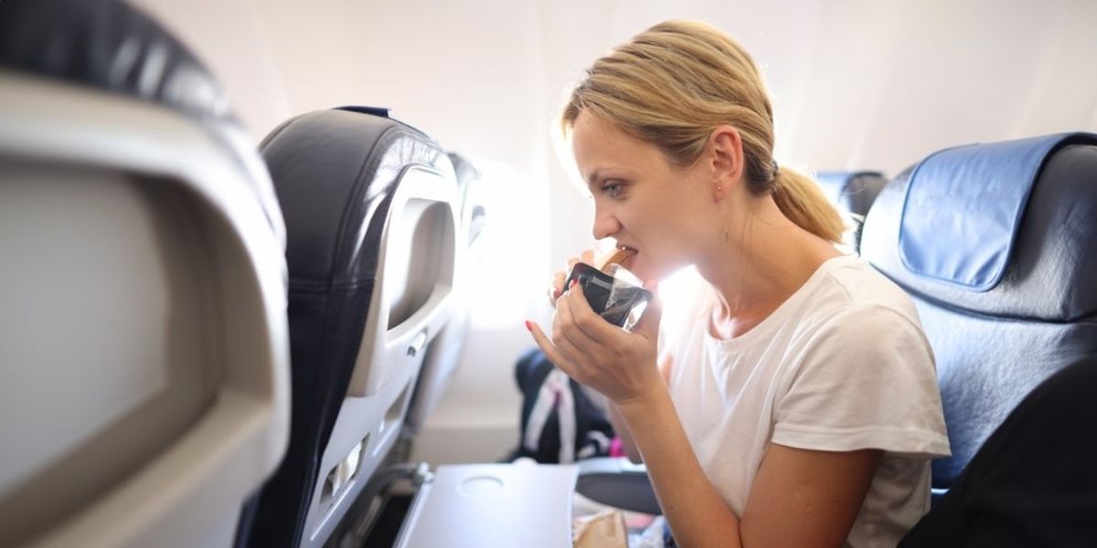 egy nő eszik a repülőn