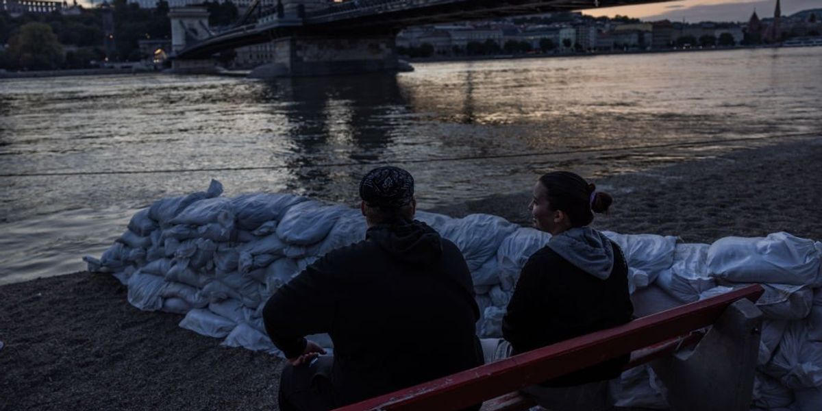 egy pár ül a megáradt Duna és homokzsákok mellett Budapesten 2024. szeptember 17-én
