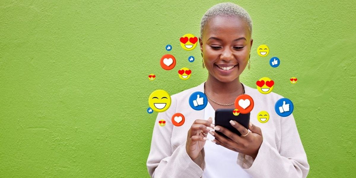 Fekete nő kezében mobiltelefonnak, körülötte emojik