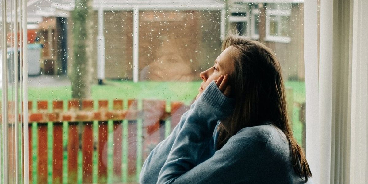 búskomor nő ül az ablakban és nézi a hóesést