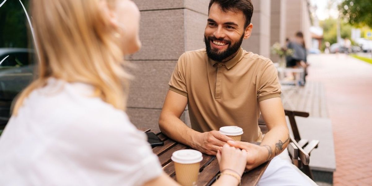 egy férfi megfogja egy nő kezét és rámosolyog egy randin