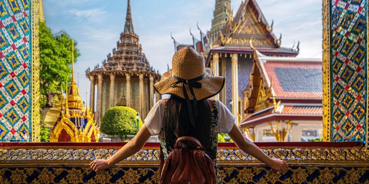 Bankgokban ablakon kinéző turista csodálja a város szépségeit