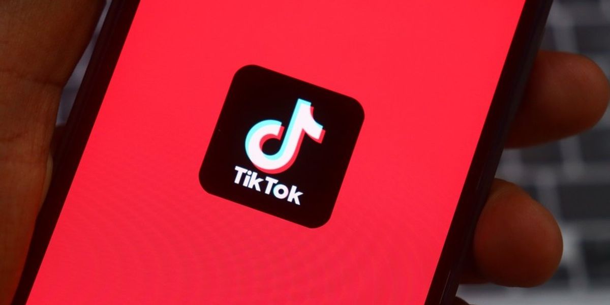 Mobiltelefont tartó kéz, a képernyőn TikTok-logóval