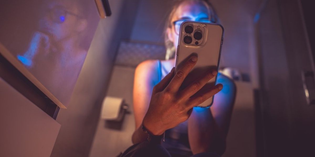 Sötét wcben telefonozó személy