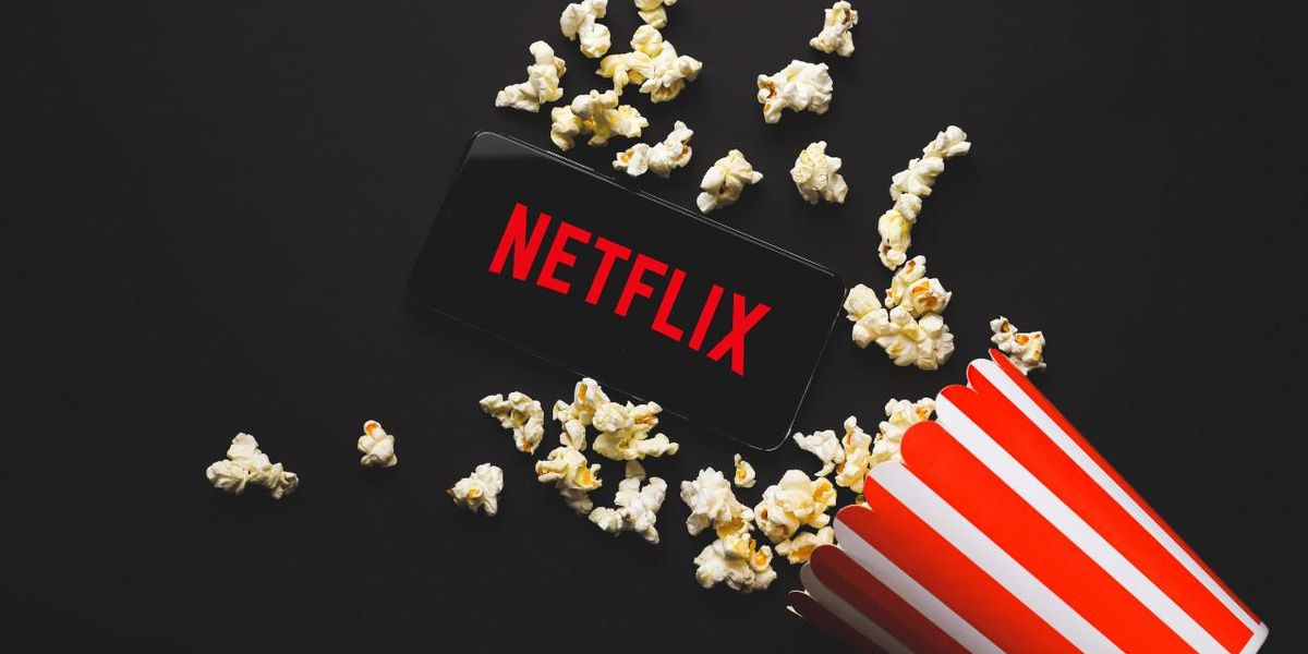 Mobilképernyő a Netflix logójával, egy adag popcorn mellett