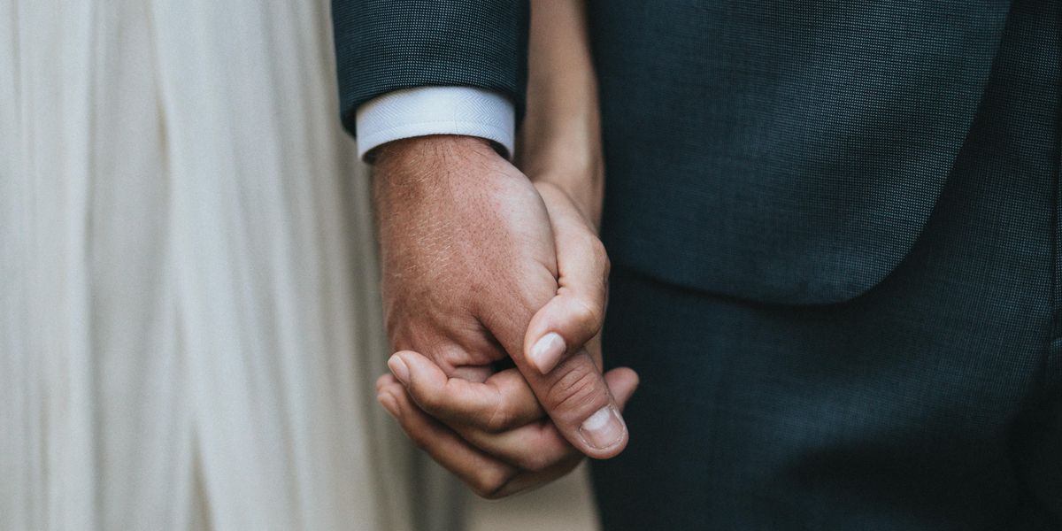 man in suit holding hands with woman in white skirt