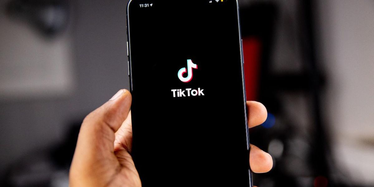 iPhone-t tartó kéz, a mobilon futó TikTok alkalmazással