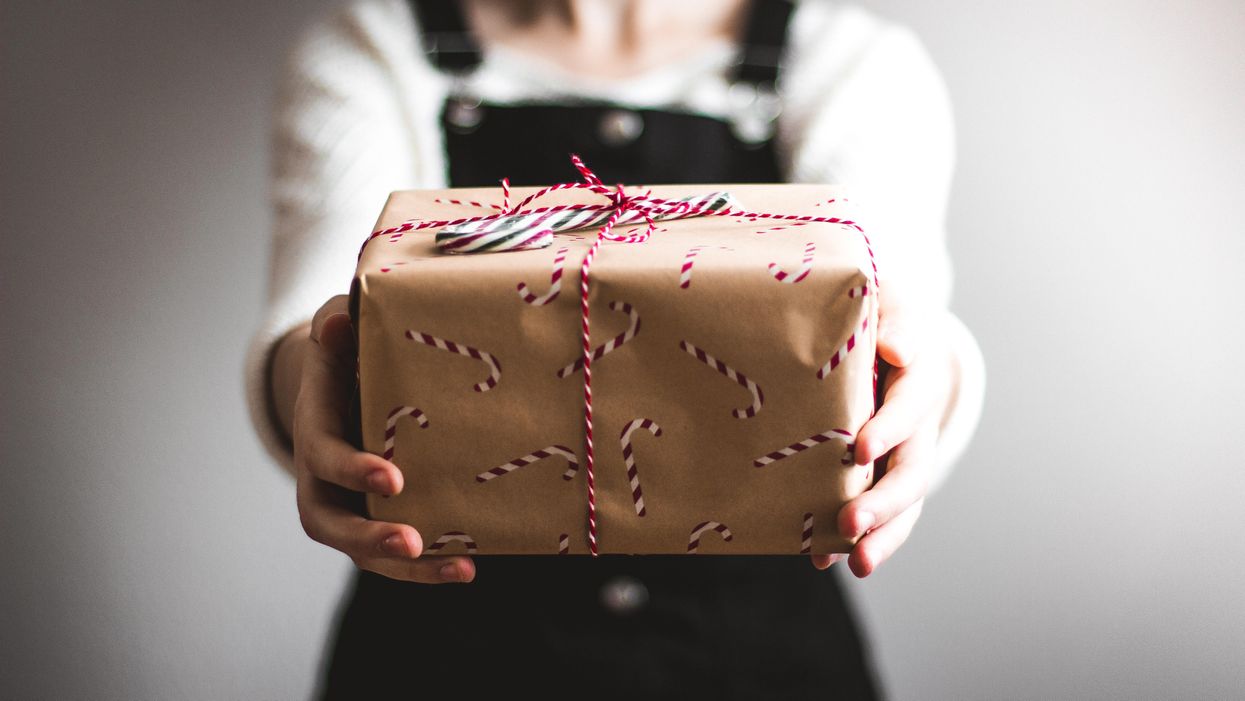 egy lány egy becsomagolt karácsonyi ajándékot nyújt át