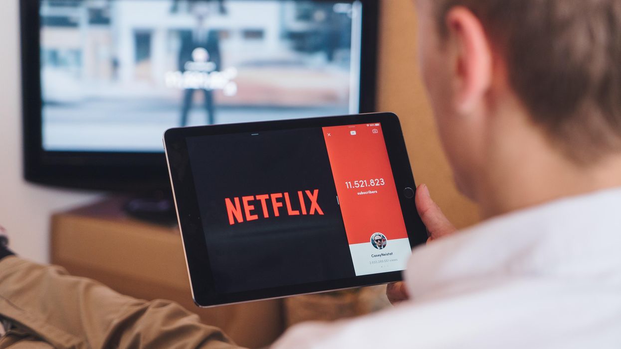 egy férfi egy tabletet tart a kezében, amin a Netflix oldala van megnyitva