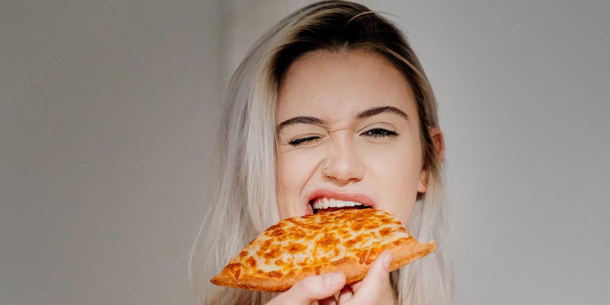 woman in white tank top holding pizza