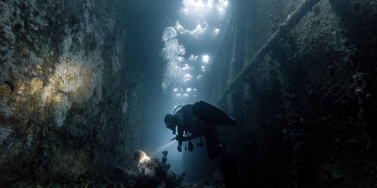 Egy búvár zseblámpával kémleli a víz alatti talajt