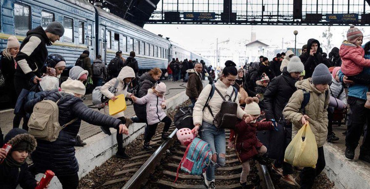 Az orosz invázió elől menekülő emberek százai várakoznak a Lengyelországba tartó vonatra a lvivi központi pályaudvaron február 27-én