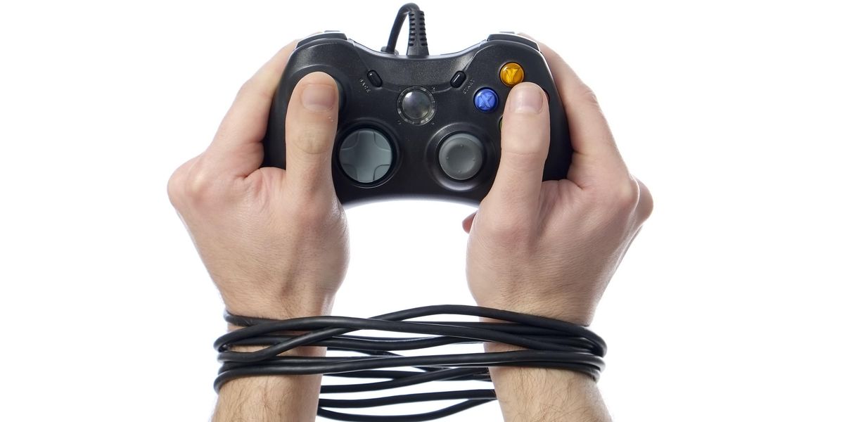 Béklyóba kötött, videojáték kontrollert tartó kezek