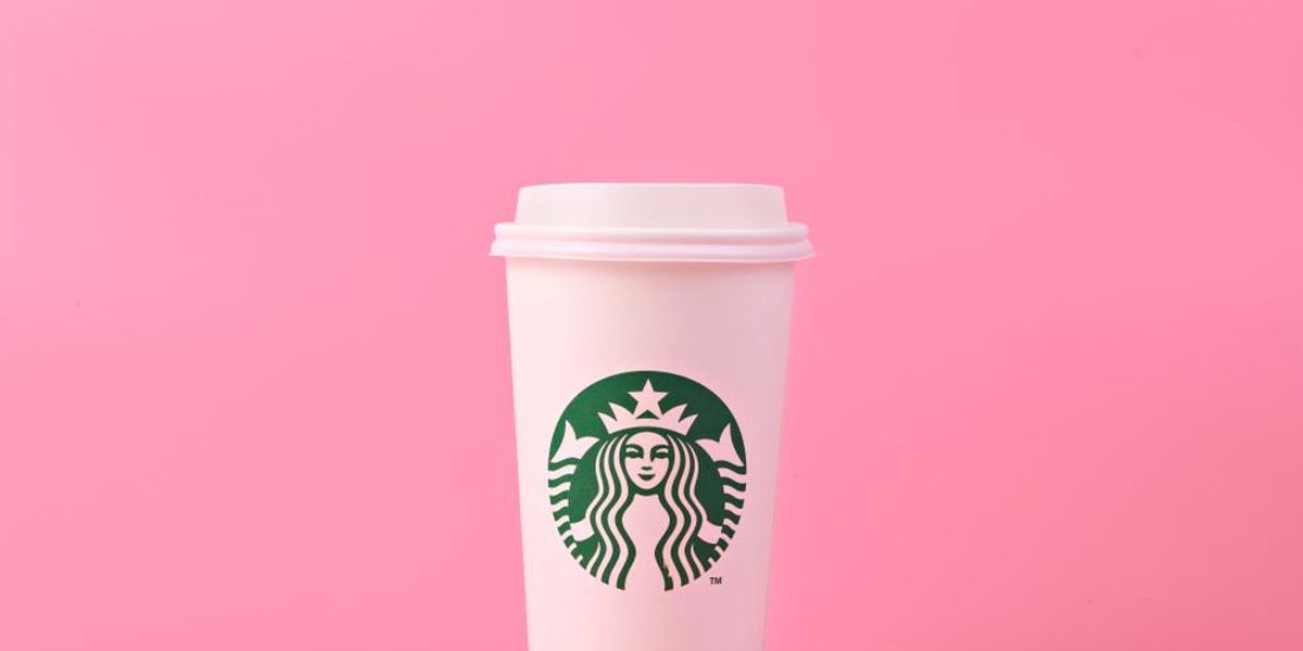 Starbucks logóval ellátott, egyszer használatos pohár rózsaszín háttér előtt