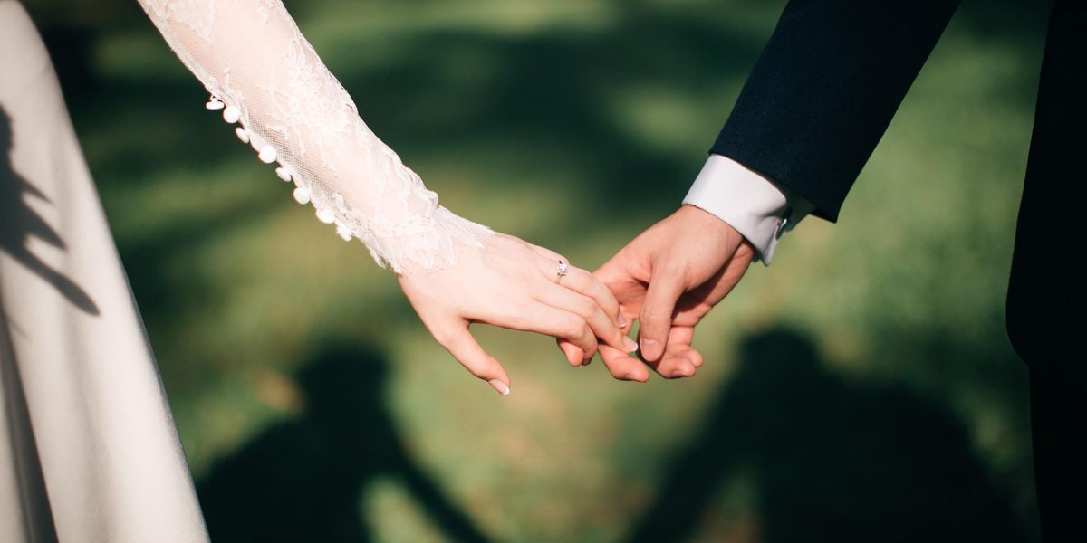 Férj és feleség fogják egymás kezét az esküvőjükön