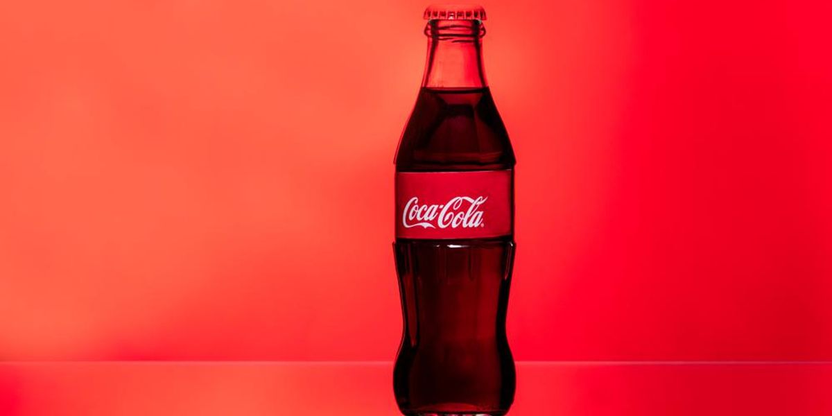 Coca-Cola ital üvegpalack piros színű háttér előtt