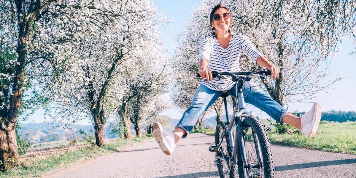 Boldog, mosolygó nő vidáman biciklizik az úton