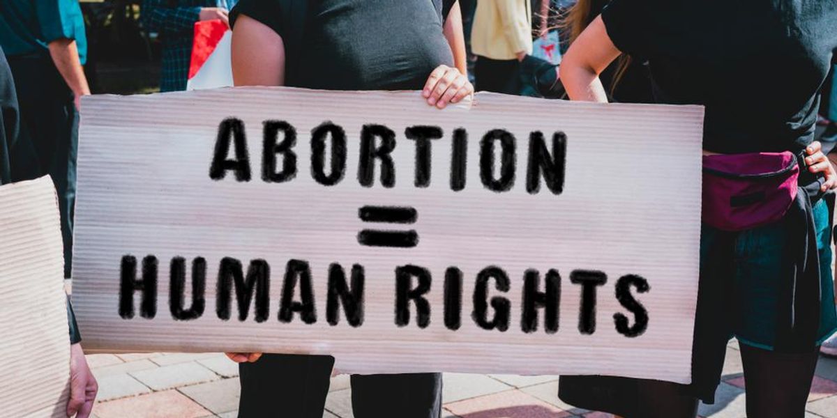 Az " Abortusz = emberi jogok " feliratú  transzparenss tartó női kéz. 