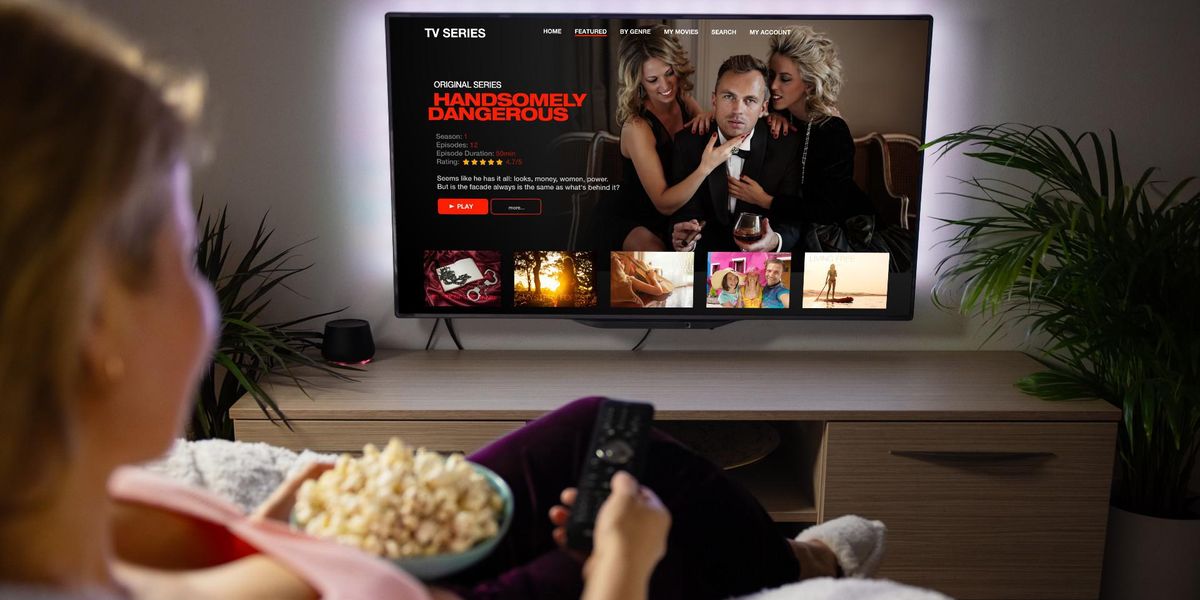streamelt sorozatot néz egy nő popcornnal a kanapéján