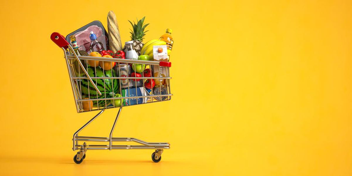 Bevásárló kocsi megpakolva élelmiszerrel, sárga háttér
