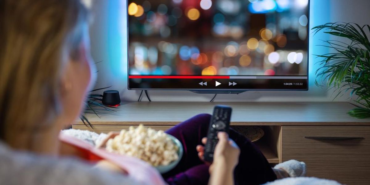 Tv-t néz egy szőke hajú nő, popcorn az ölében