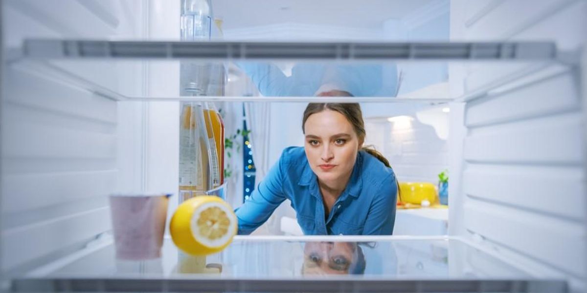 Egy nő kinyitja a majdnem üres hűtőszekrényét