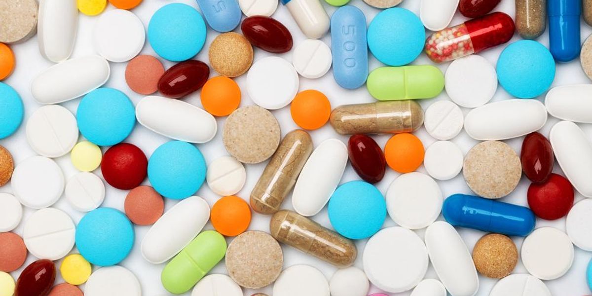 Különböző színes gyógyszerek és tabletták fehér asztalon