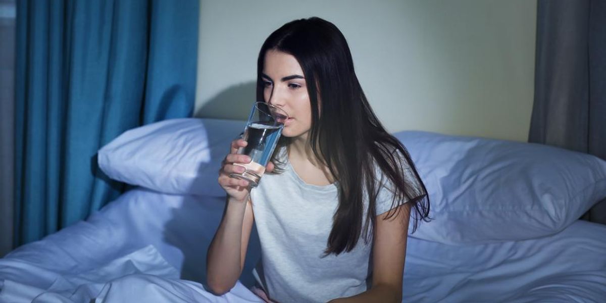 Fiatal nő pohár vizet iszik lefekvés előtt