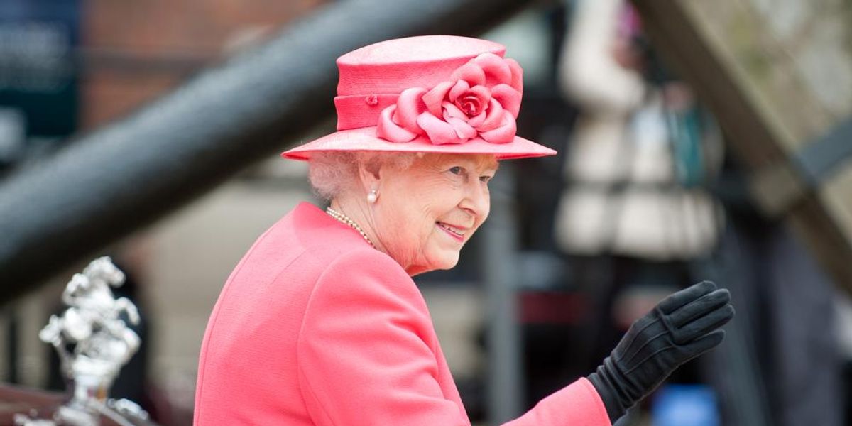 II. Erzsébet brit királynő rózsaszín kosztümben és kalapban integet