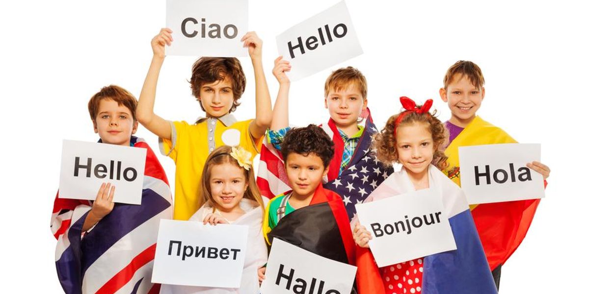 Gyerekek különböző nyelvű üdvözlő táblákat tartanak a kezükben