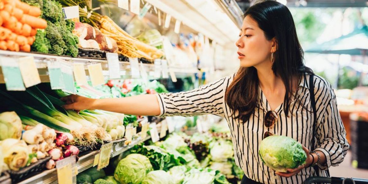 Zöldségek és gyümölcsök között válogató nő a szupermarketben