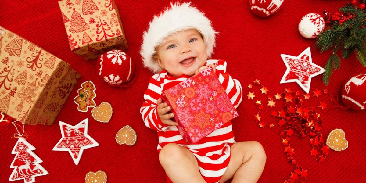 Karácsonyi díszek és ajándékok között fekvő baba
