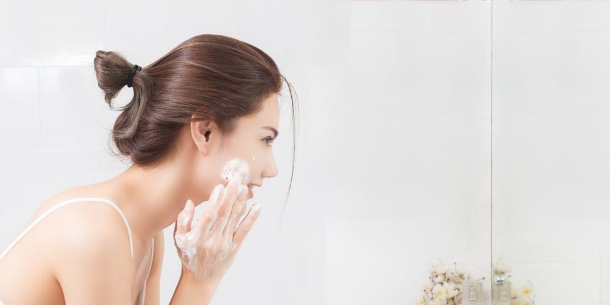 Barna hajú nő mossa az arcát a tükör előtt