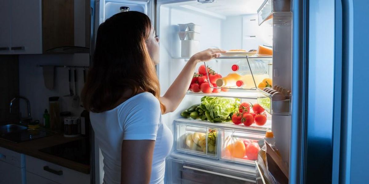 Egy nő éjjel kinyitja a hűtőjét