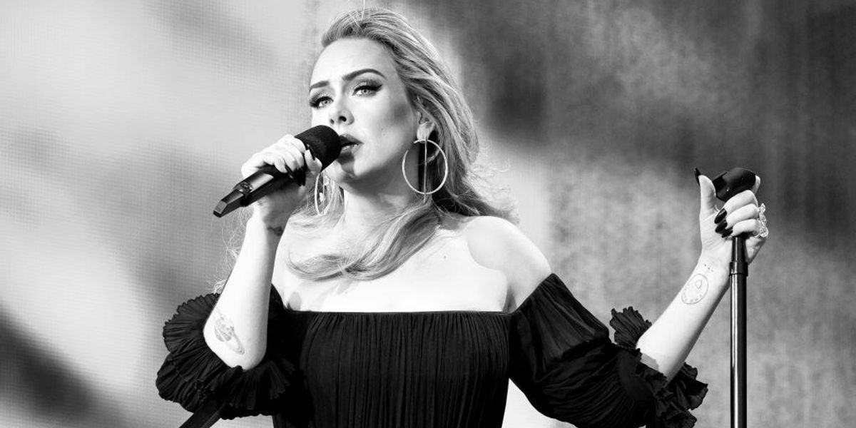 Adele énekel mikrofonba, fekete ruhában