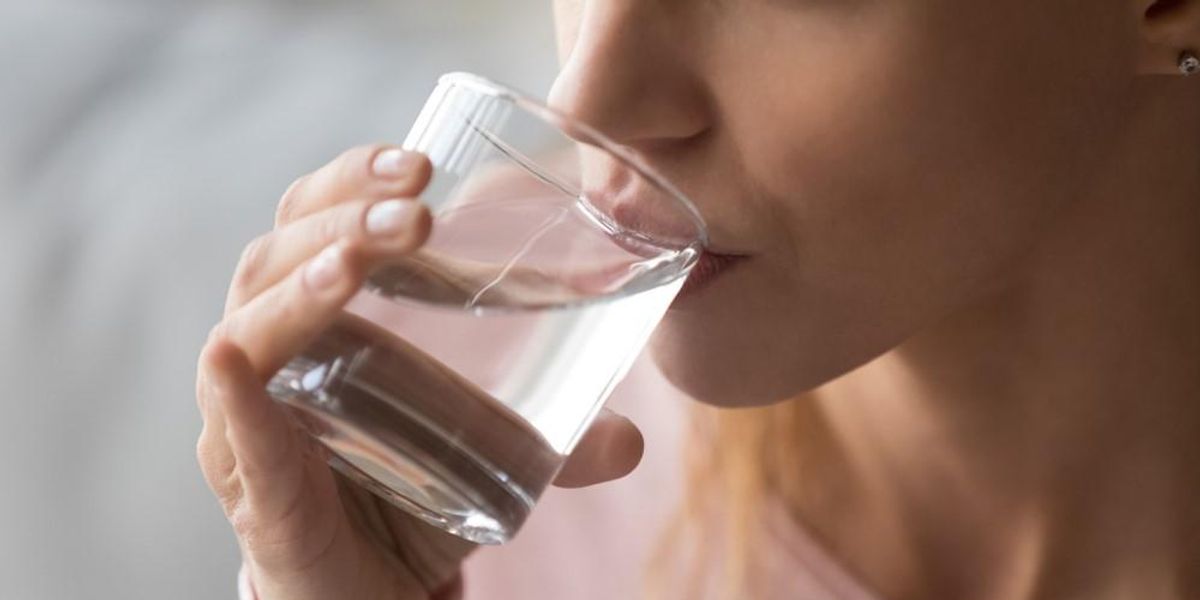 Egy nő vizet iszik egy pohárból