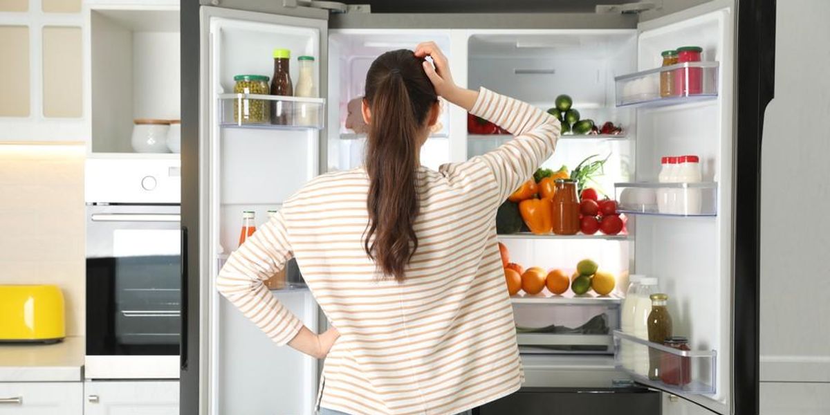 Egy nő gondolkodik a hűtőszekrénye előtt