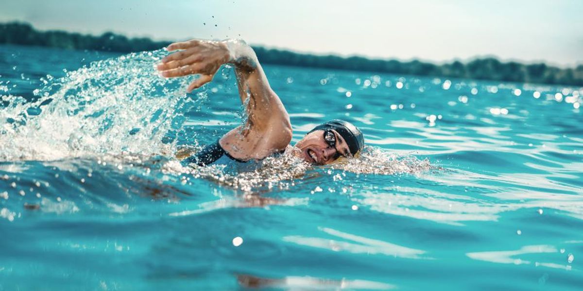Profi triatlonista úszik a folyó nyílt vizén 