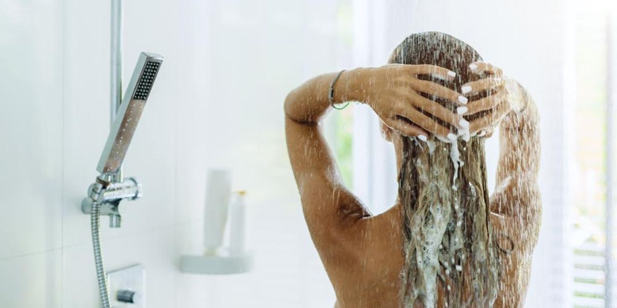 Nő zuhanyzás közben a haját mossa