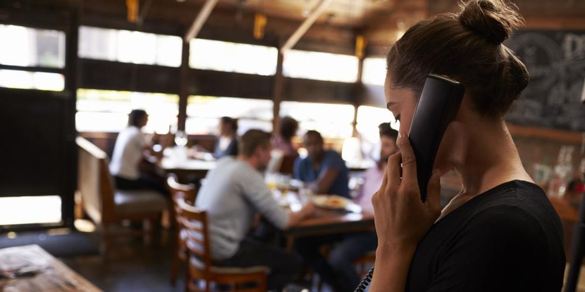 Fiatal pincérnő felveszi a foglalást telefonon az étteremben