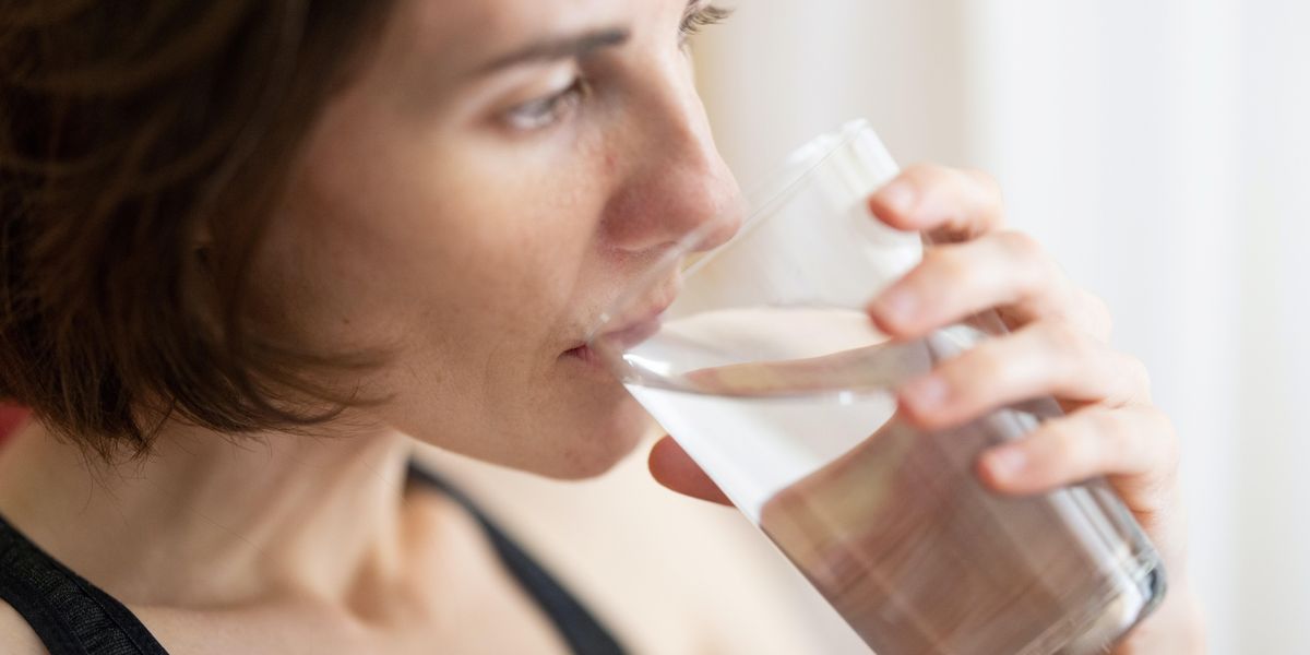 Egy nő vizet iszik egy pohárból