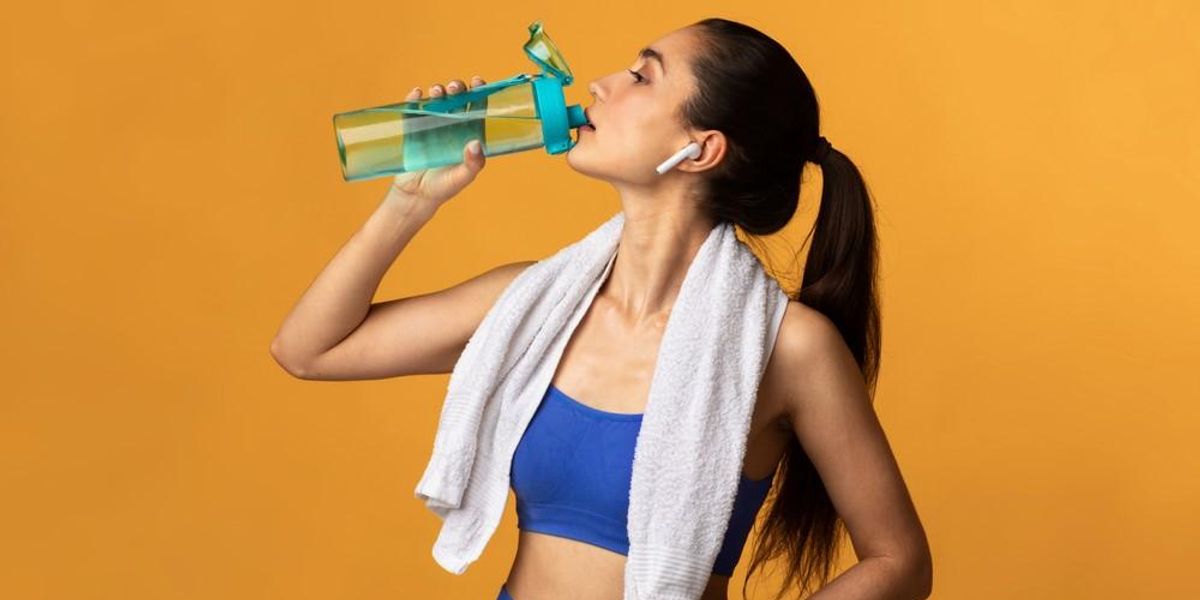 Egy nő edzés közben az üvegéből iszik