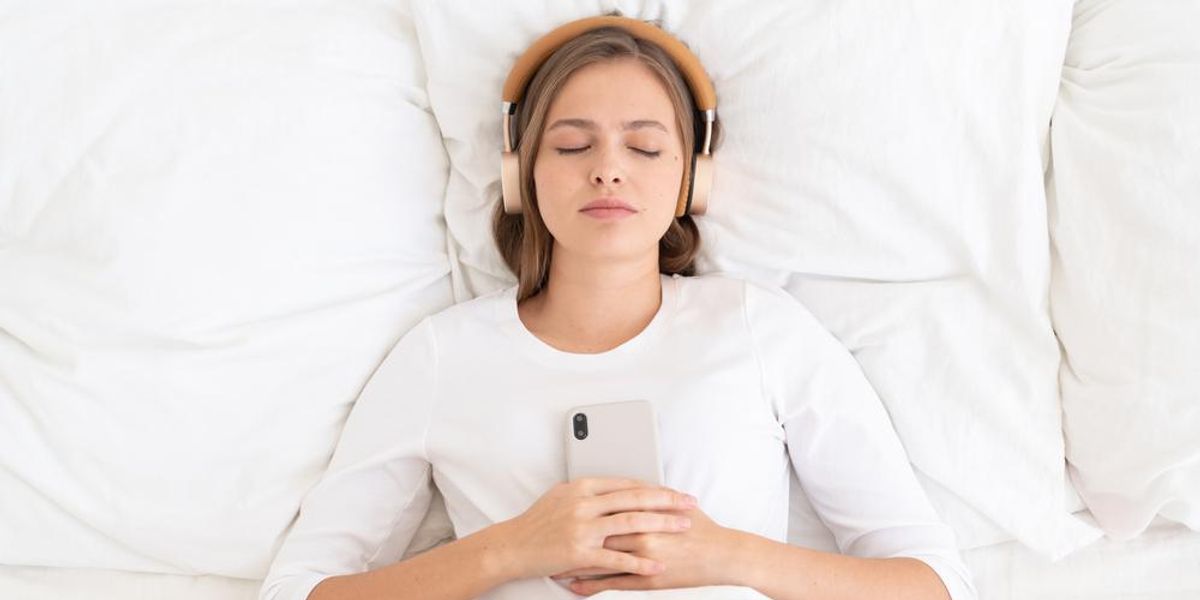 Fejhallgatóval alvó nő, kezében mobiltelefon
