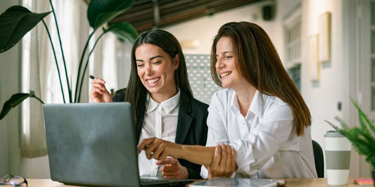 Női kollégák boldogan ülnek a laptop előtt