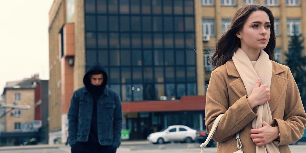 Egy kapucnis férfi követ egy nőt az utcán