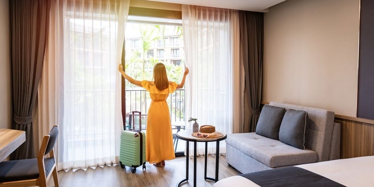 Nő hotel szoba függönyét húzza el