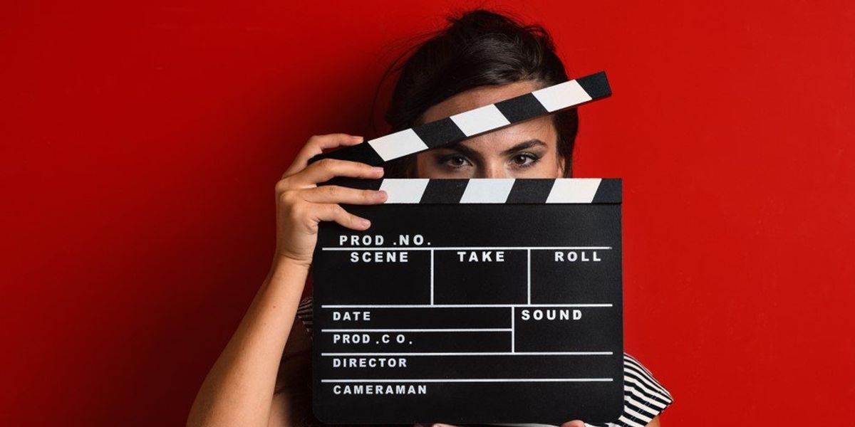 Egy nő egy filmes csapót tart a kezében