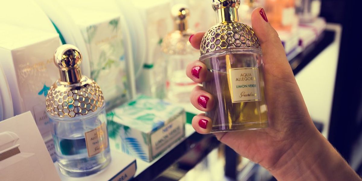 Guerlain parfümös üveget tart egy női kéz