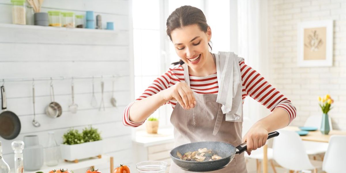 Barna hajú nő főz a konyhában csíkos pólóban
